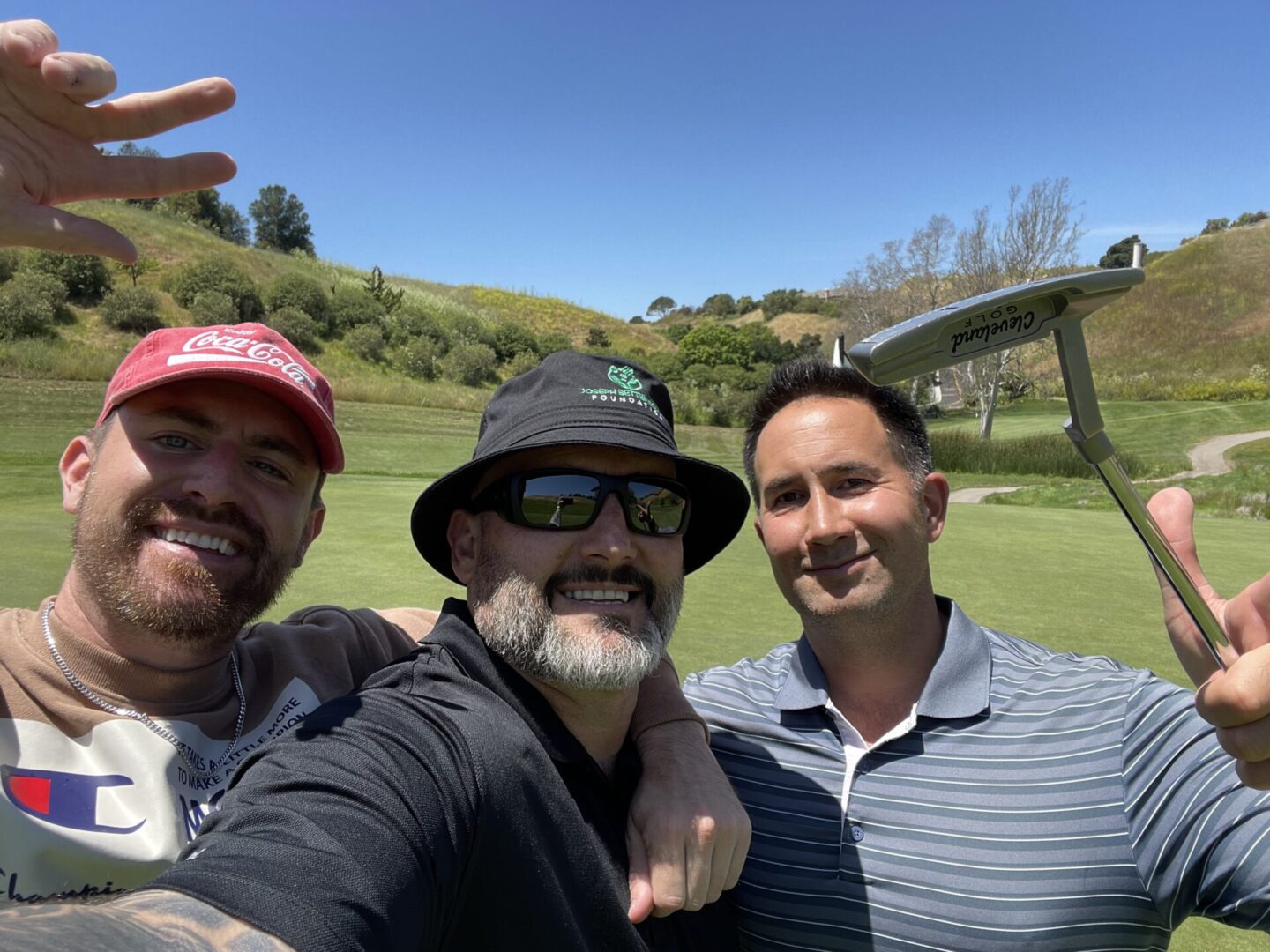 Three men pose for a picture on the golf course.
