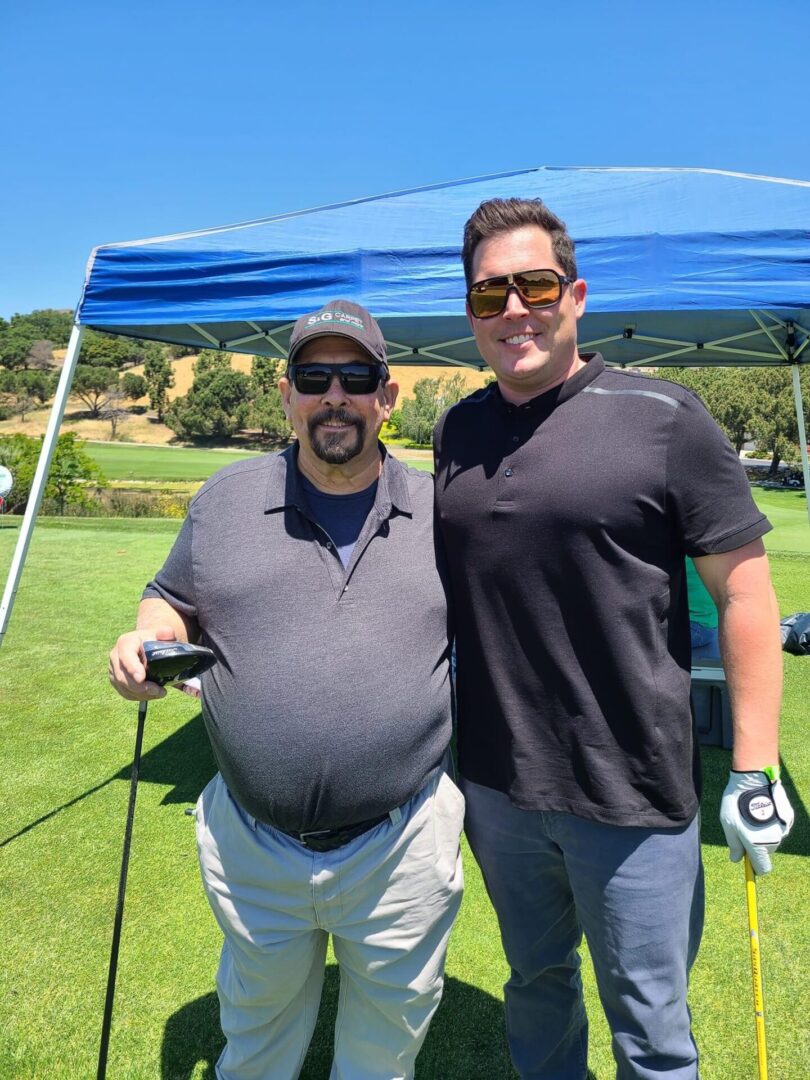 Two men standing next to each other on a golf course.