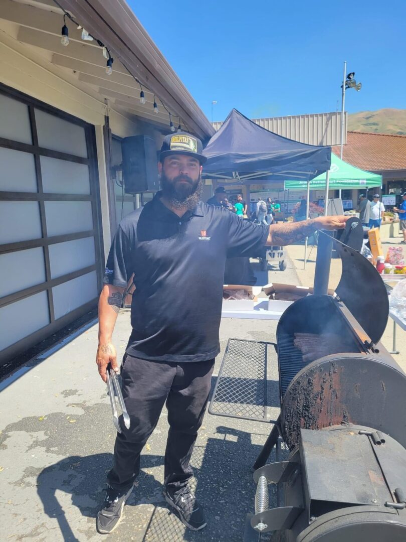 A man standing next to an open grill.